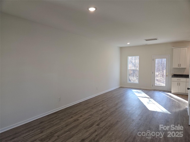 unfurnished living room featuring baseboards, visible vents, dark wood-type flooring, and recessed lighting