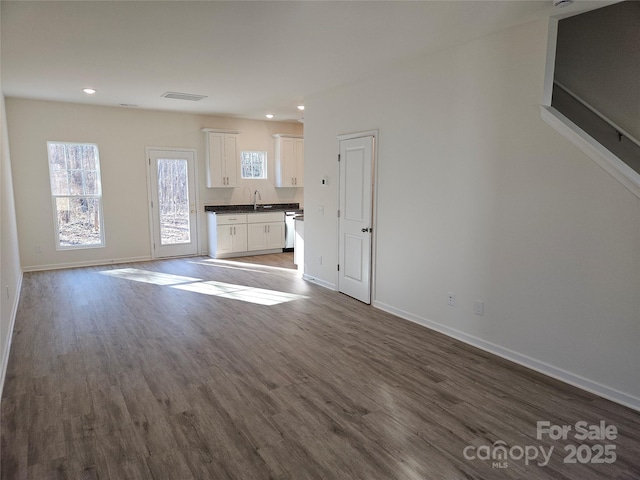 unfurnished living room featuring recessed lighting, a sink, wood finished floors, visible vents, and baseboards