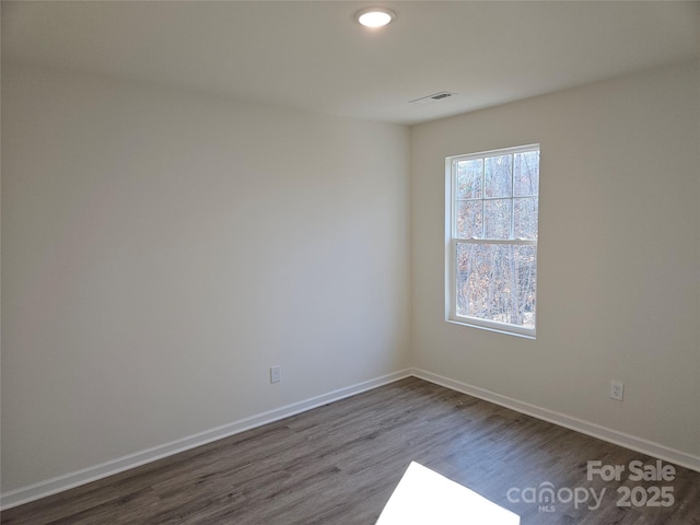 spare room with visible vents, baseboards, and wood finished floors