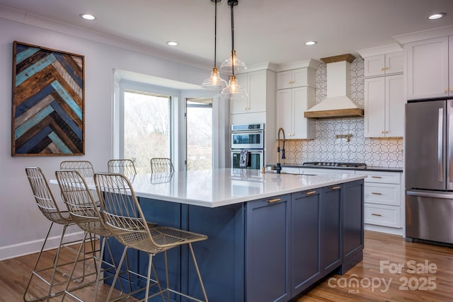 kitchen featuring stainless steel appliances, wood finished floors, white cabinets, custom exhaust hood, and tasteful backsplash