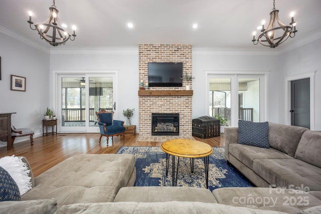 living area featuring a brick fireplace, a wealth of natural light, and a notable chandelier