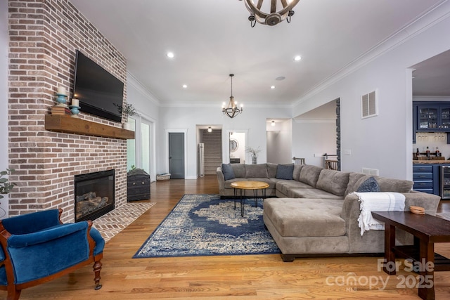 living area with a chandelier, visible vents, a fireplace, and wood finished floors