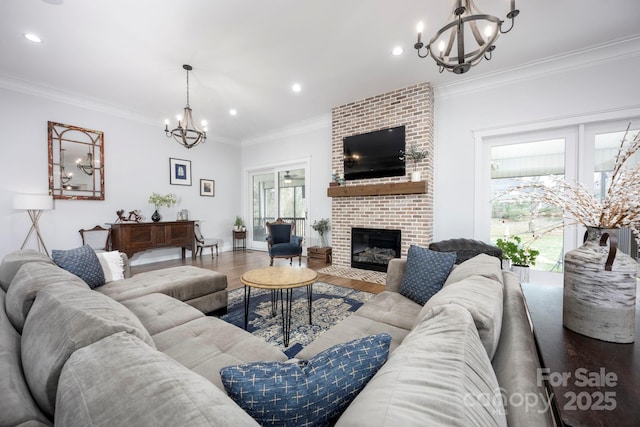 living area featuring recessed lighting, a fireplace, wood finished floors, ornamental molding, and an inviting chandelier