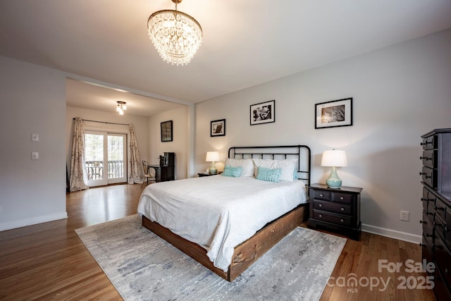 bedroom with baseboards, a chandelier, and wood finished floors