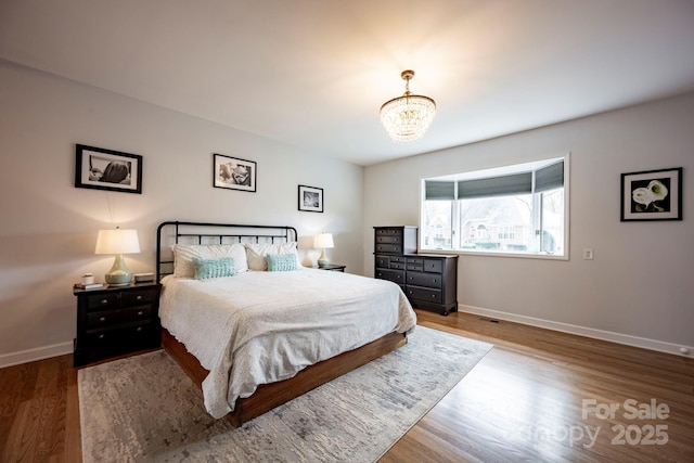 bedroom with a notable chandelier, baseboards, and wood finished floors