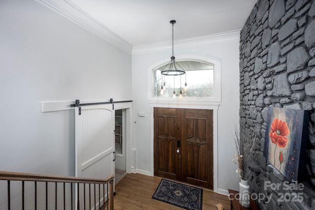 foyer entrance with baseboards, a barn door, wood finished floors, and crown molding