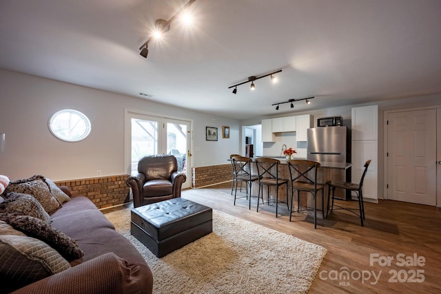 living area with light wood finished floors, visible vents, and wainscoting