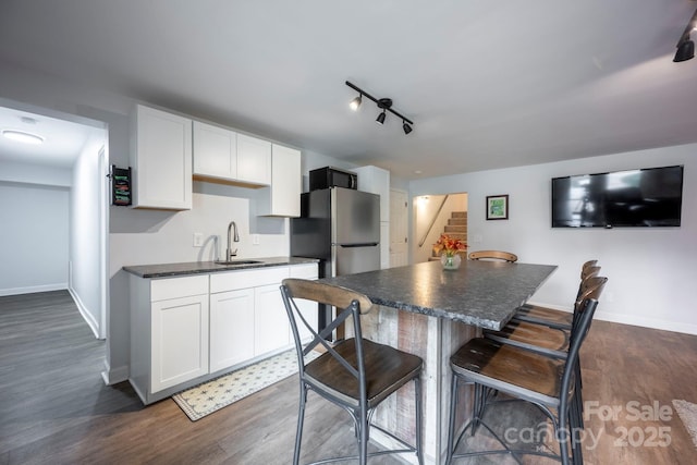 kitchen featuring dark wood-style floors, dark countertops, white cabinets, and a kitchen breakfast bar