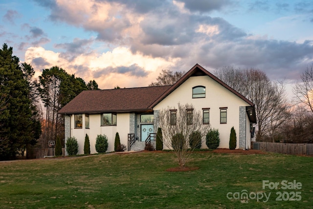 view of front of house with a front lawn, fence, and stucco siding