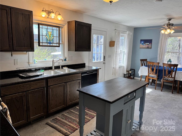 kitchen featuring dishwasher, dark countertops, a sink, and plenty of natural light