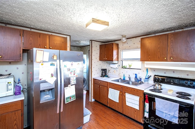 kitchen featuring stainless steel fridge with ice dispenser, white microwave, under cabinet range hood, a sink, and range with electric stovetop