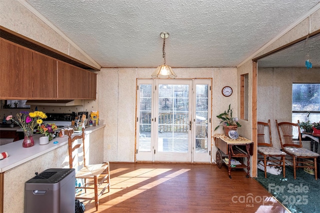 interior space featuring under cabinet range hood, a textured ceiling, light countertops, and wood finished floors