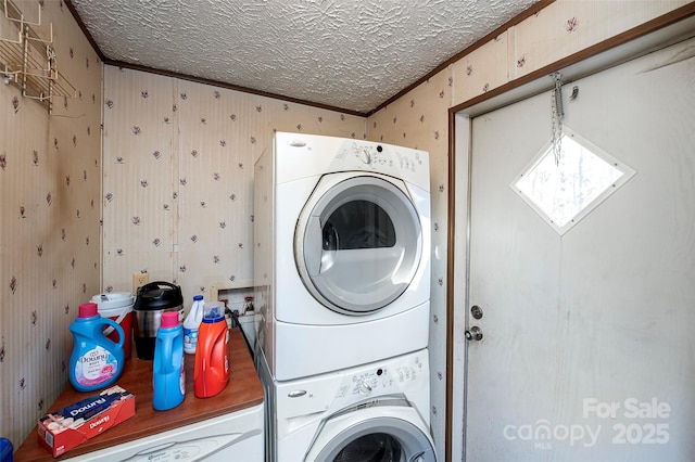 laundry area featuring laundry area, wallpapered walls, stacked washer and dryer, ornamental molding, and a textured ceiling