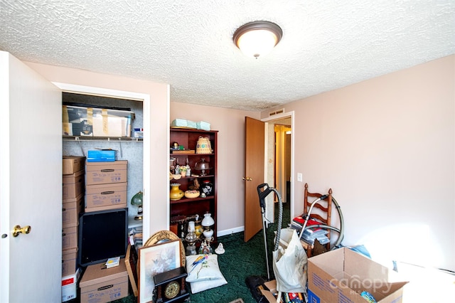 interior space with a textured ceiling, carpet floors, and baseboards