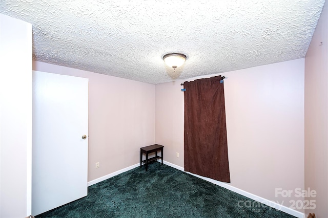 spare room with carpet flooring, a textured ceiling, and baseboards