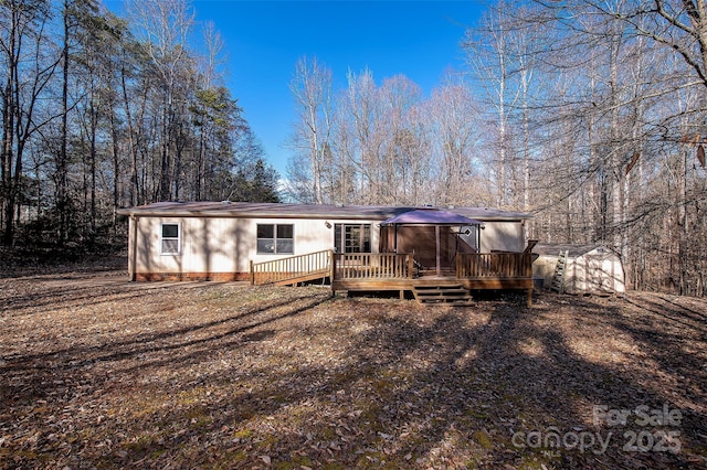 rear view of property with a storage unit, a deck, and an outbuilding