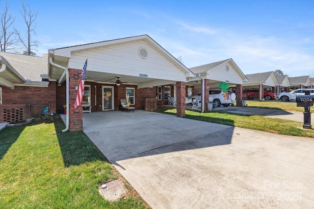 view of front of property with brick siding, a front lawn, ceiling fan, and driveway