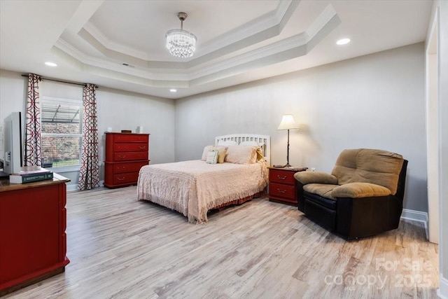 bedroom featuring a raised ceiling, light wood-style floors, a chandelier, and crown molding