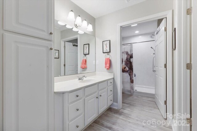 full bathroom with vanity, a shower with shower curtain, and wood finished floors