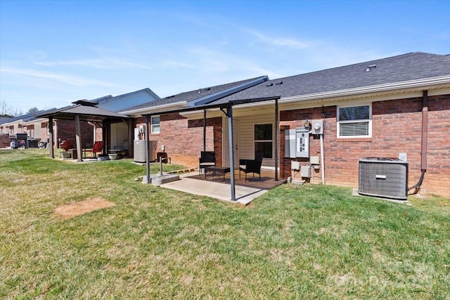 rear view of property featuring brick siding, a gazebo, central AC unit, a yard, and a patio