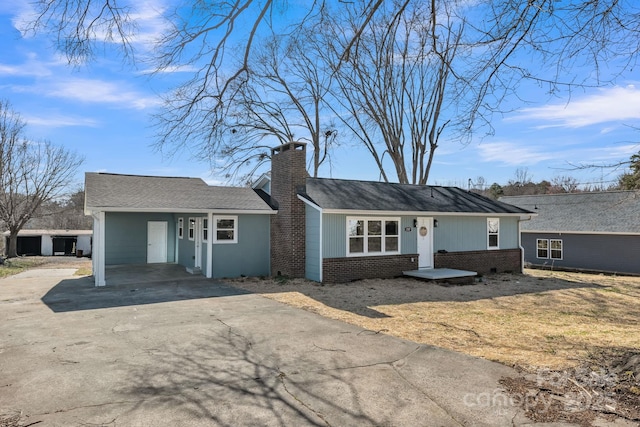 ranch-style home featuring brick siding, driveway, and a chimney