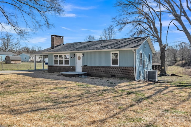 view of front of property with central AC unit, brick siding, crawl space, a front lawn, and a chimney