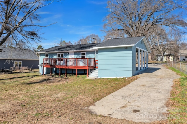 back of property featuring a deck, fence, a yard, driveway, and roof with shingles