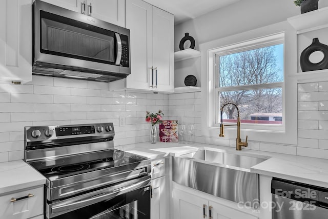 kitchen with stainless steel appliances, white cabinets, and light stone countertops