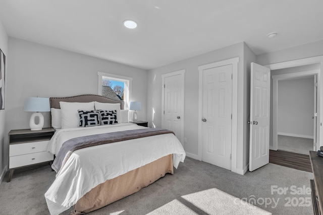 carpeted bedroom featuring baseboards and two closets