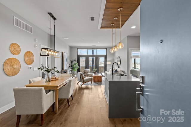 kitchen with hardwood / wood-style floors, a sink, visible vents, and decorative light fixtures