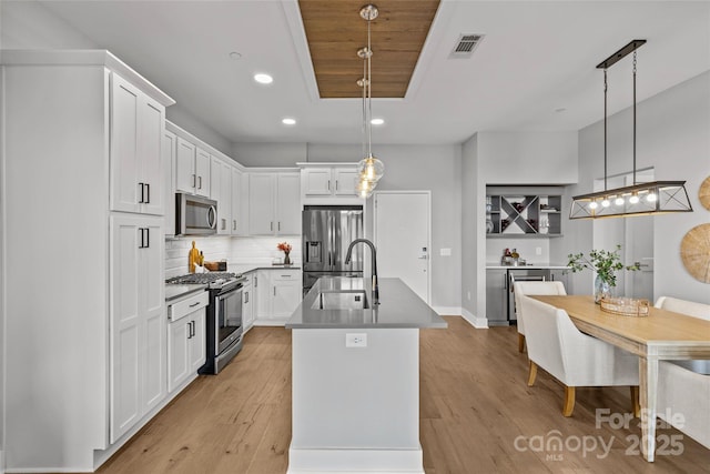 kitchen featuring light wood finished floors, appliances with stainless steel finishes, decorative backsplash, and a sink