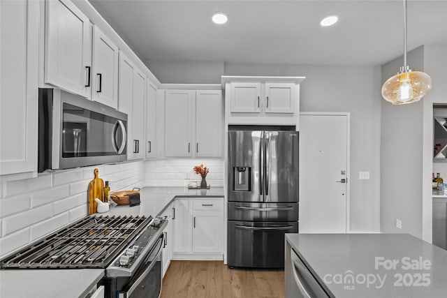 kitchen with recessed lighting, light wood-style flooring, decorative backsplash, appliances with stainless steel finishes, and white cabinets