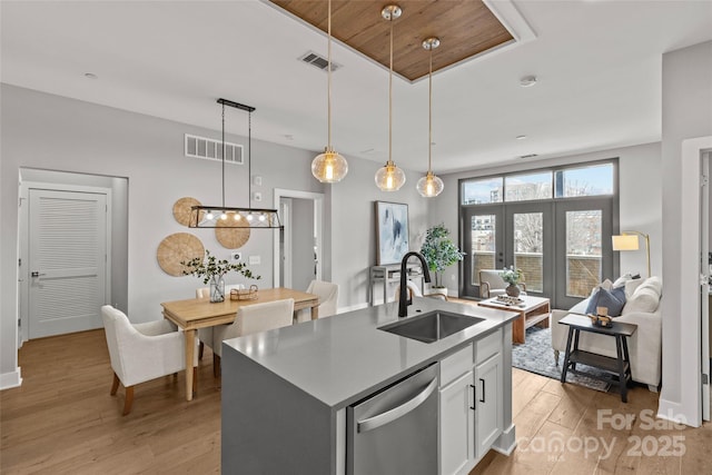 kitchen with visible vents, light wood-style floors, white cabinets, a sink, and dishwasher