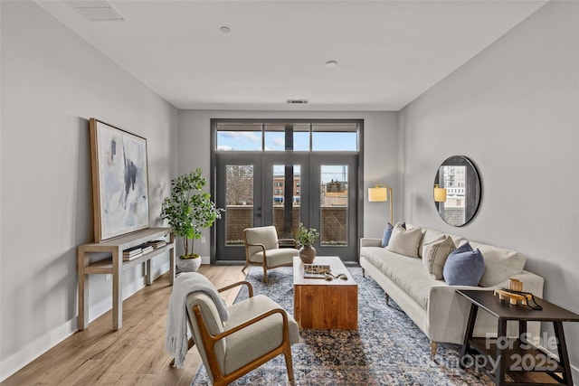 living room with baseboards, visible vents, and light wood-style floors