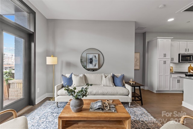 living area with visible vents, baseboards, dark wood-type flooring, and recessed lighting