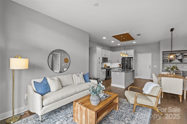 living room with attic access, visible vents, dark wood finished floors, baseboards, and recessed lighting