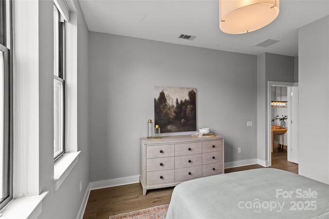 bedroom featuring wood finished floors, visible vents, and baseboards