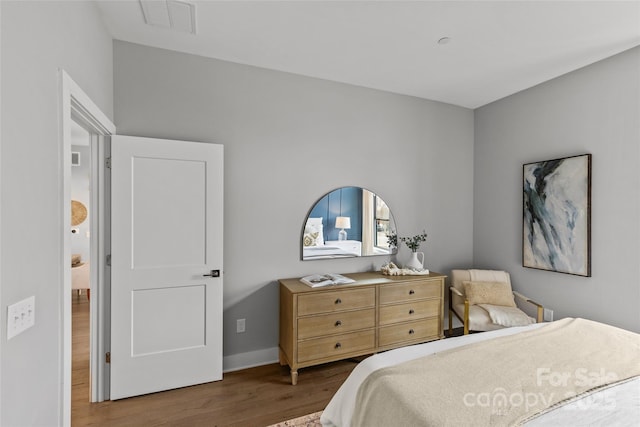 bedroom with baseboards, visible vents, and wood finished floors