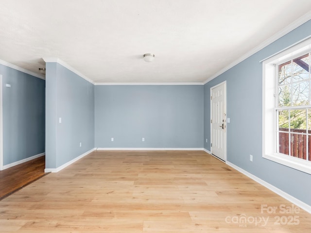 spare room with light wood-type flooring, baseboards, and crown molding