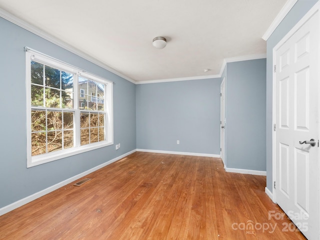 unfurnished room with ornamental molding, visible vents, baseboards, and wood finished floors