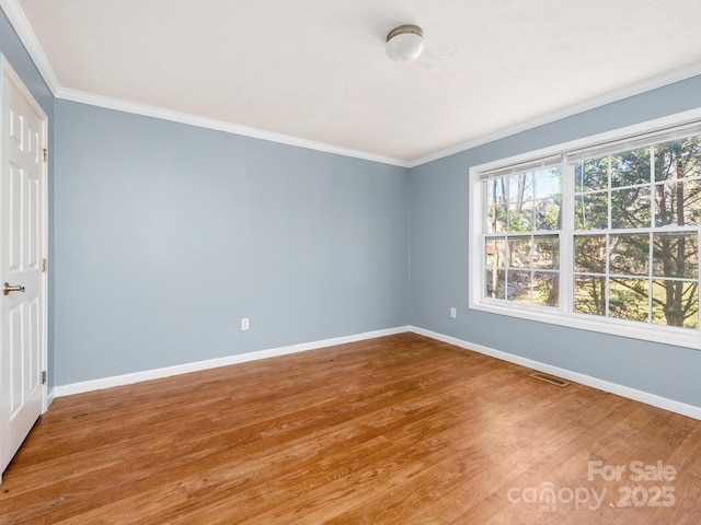 unfurnished bedroom with baseboards, visible vents, wood finished floors, and ornamental molding