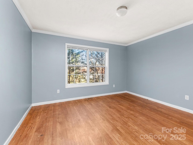 spare room featuring ornamental molding, wood finished floors, visible vents, and baseboards