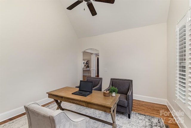 office featuring light wood-type flooring, baseboards, arched walkways, and a ceiling fan