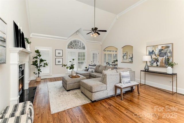 living room with a lit fireplace, wood finished floors, and baseboards