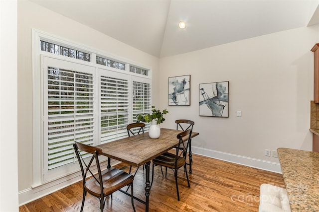 dining room with lofted ceiling, light wood finished floors, and baseboards