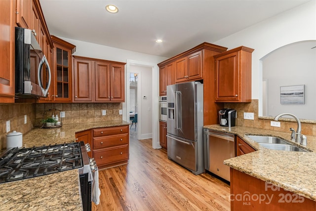 kitchen featuring appliances with stainless steel finishes, light stone countertops, light wood-type flooring, a sink, and recessed lighting