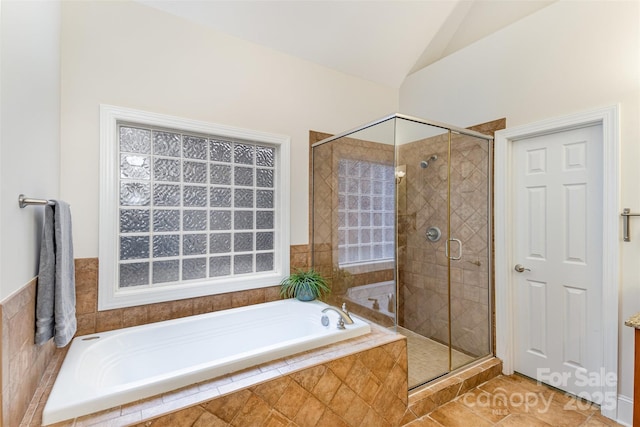 bathroom featuring lofted ceiling, a garden tub, a shower stall, and tile patterned floors