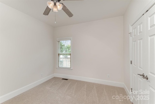 empty room featuring baseboards, ceiling fan, visible vents, and light colored carpet