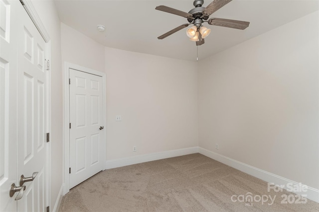 unfurnished room featuring a ceiling fan, light colored carpet, and baseboards