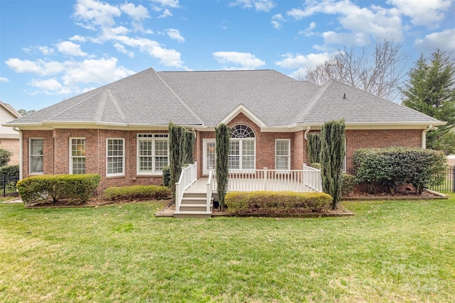 ranch-style home featuring a shingled roof, a front yard, and brick siding